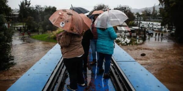 Personas protegiéndose de la intensa lluvia, graficando el complejo pronóstico del tiempo de mañana en la capital