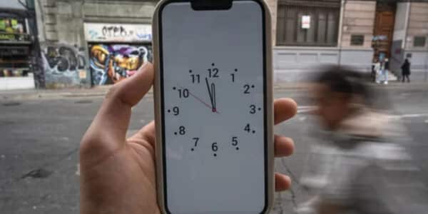 Reloj marcando el cambio de hora oficial en Chile junto a un mapa de husos horarios sudamericanos.