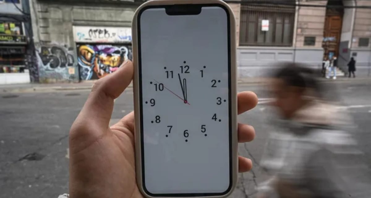 Reloj marcando el cambio de hora oficial en Chile junto a un mapa de husos horarios sudamericanos.