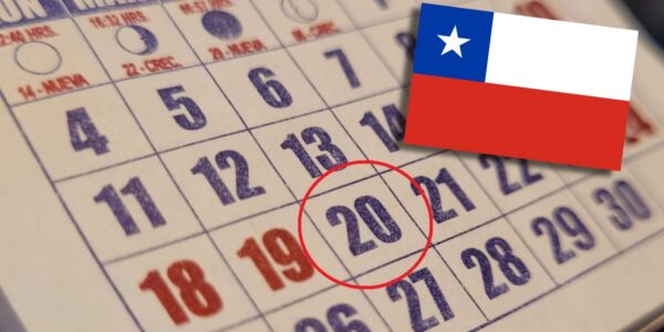Primer plano de un calendario de papel con varios días numerados; el 20 está rodeado con un círculo rojo y aparece la bandera de Chile sobreimpresa en la parte superior derecha.