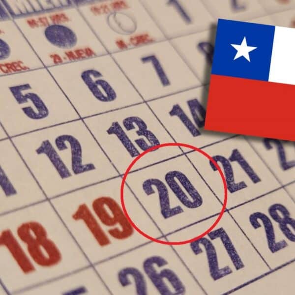 Primer plano de un calendario de papel con varios días numerados; el 20 está rodeado con un círculo rojo y aparece la bandera de Chile sobreimpresa en la parte superior derecha.