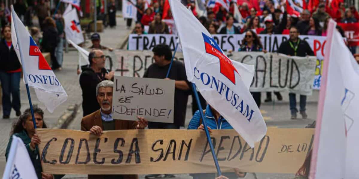 Funcionarios de la salud municipal marchando por las calles con pancartas y banderas gremiales, en alusión al paro nacional de 48 horas convocado por la Confusam en distintas ciudades del país para exigir un aumento en el financiamiento per cápita de la atención primaria, en medio del ingreso del Presupuesto 2027 al Congreso Nacional y con turnos éticos operativos para urgencias.