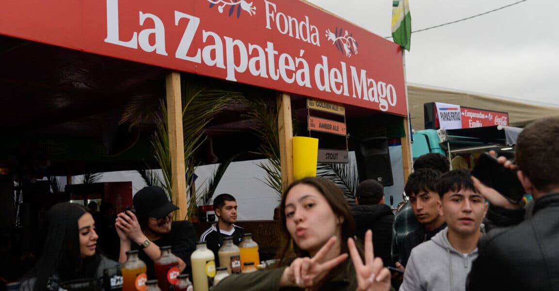 Letrero rojo de la fonda La Zapateá del Mago junto a asistentes en Fiestas Patrias 2026