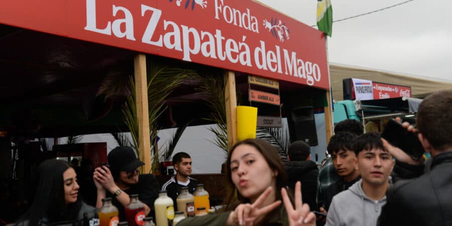 Letrero rojo de la fonda La Zapateá del Mago junto a asistentes en Fiestas Patrias 2026