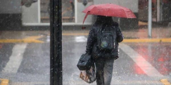 Personas caminando bajo la lluvia en una calle de Santiago, imagen ilustrativa del sistema frontal previsto para octubre de 2026.