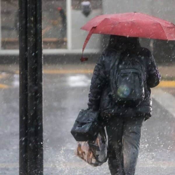 Personas caminando bajo la lluvia en una calle de Santiago, imagen ilustrativa del sistema frontal previsto para octubre de 2026.